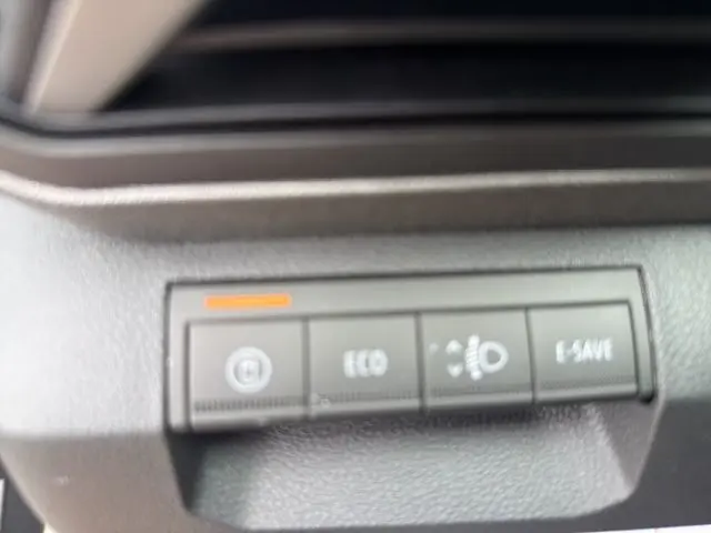 Gros plan sur les boutons de commande du tableau de bord gris foncé du Dacia Bigster hybride, avec indicateur orange allumé.