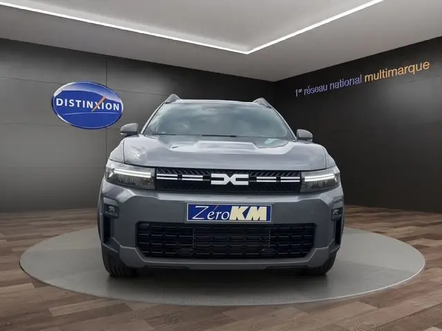 Vue de face du Dacia Bigster gris foncé avec calandre distinctive et phares LED dans un showroom.