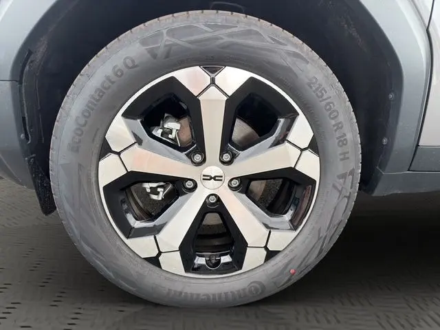 Gros plan sur la roue avant droite du Dacia Bigster gris foncé, mettant en valeur la jante alliage au design moderne.