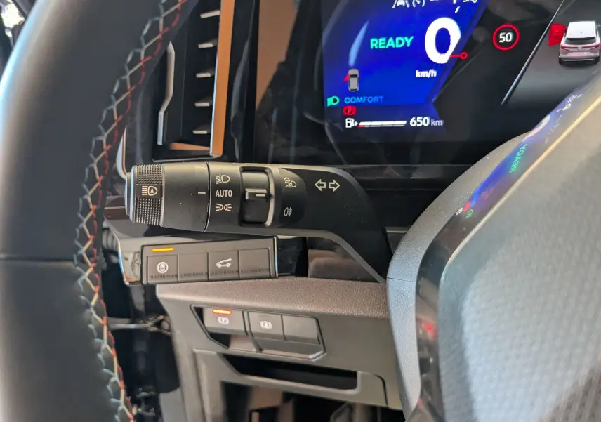 Gros plan sur la manette de clignotants et phares à gauche du volant, tableau de bord numérique bleu du Renault Espace VI noir.