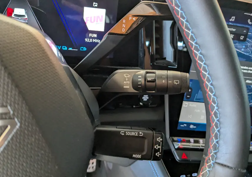 Vue rapprochée du volant noir avec surpiqûres tricolores et commandes de la Renault Espace VI E-Tech hybride 2025.