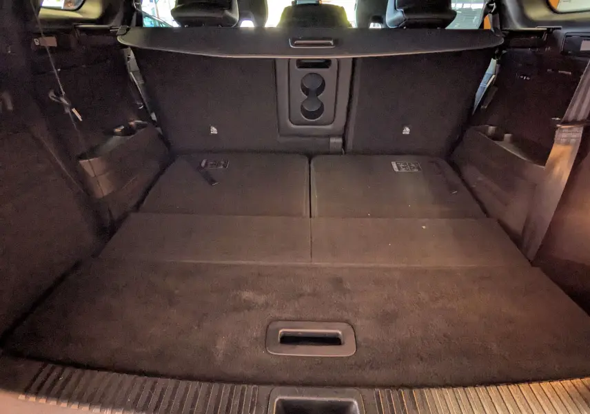 Coffre arrière ouvert en vue intérieure du Renault Espace VI noir étoile avec sièges arrière rabattus et plancher plat.