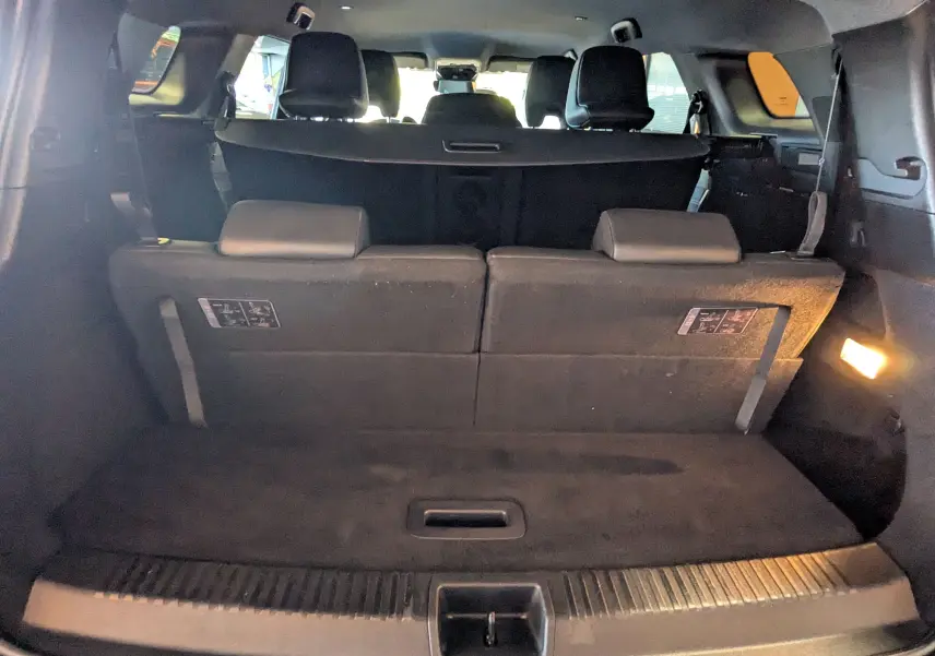 Vue depuis le coffre du Renault Espace VI noir étoile, montrant la banquette arrière relevée et l'éclairage intérieur allumé.