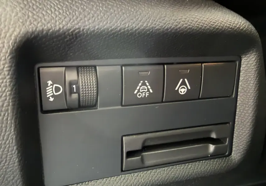 Gros plan sur les commandes noires du tableau de bord du Citroën C5 Aircross 2025, avec réglage phares et aides à la conduite.