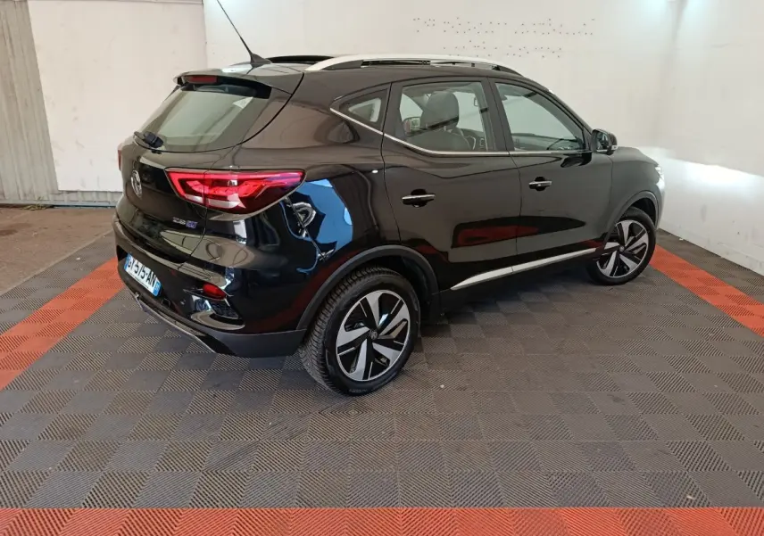 Vue 3/4 arrière droite du MG ZS Luxury 70kWh noir électrique, avec jantes distinctives et toit ouvrant visible.