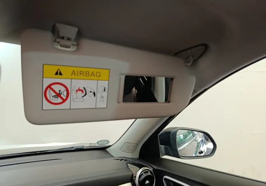 Intérieur MG Motor ZS Luxury 2024 vu côté conducteur, pare-soleil ouvert avec miroir et rétroviseur noir visible.