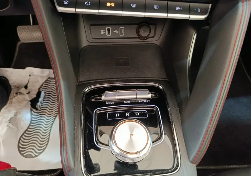 Gros plan sur la console centrale noire du MG ZS Luxury 2024, avec molette de boîte auto et surpiqûres rouges.
