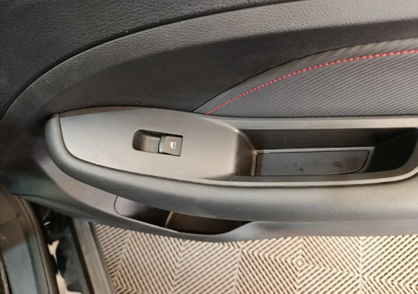 Gros plan sur la poignée intérieure côté conducteur du MG ZS Luxury noir 2024 avec bouton de commande de vitre.