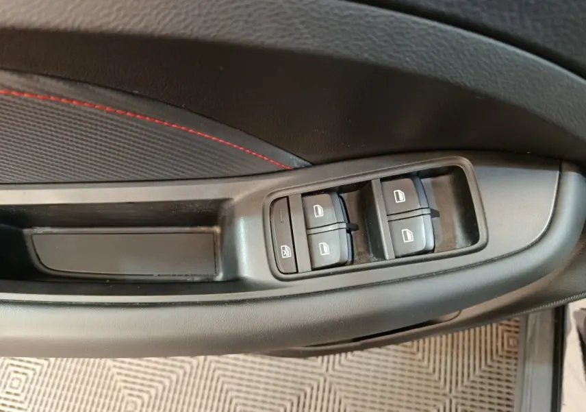 Détail des commandes de lève-vitres sur la porte côté conducteur du MG ZS Luxury noir 2024.