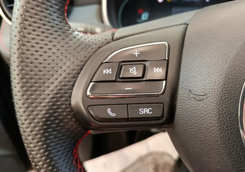 Gros plan sur les commandes gauche du volant noir perforé du MG MOTOR ZS Luxury 2024 avec boutons audio et téléphone.