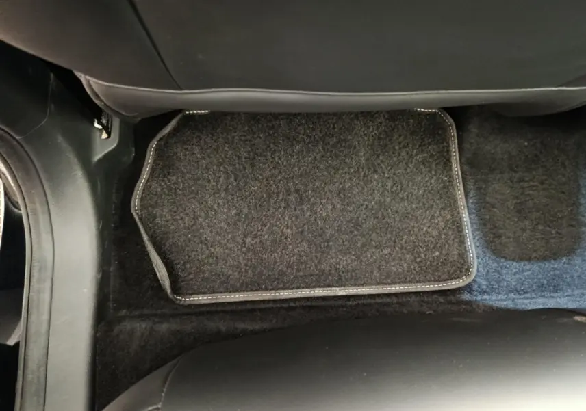 Vue plongeante sur le tapis de sol noir et la moquette du plancher côté passager arrière du MG Motor ZS Luxury 2024.