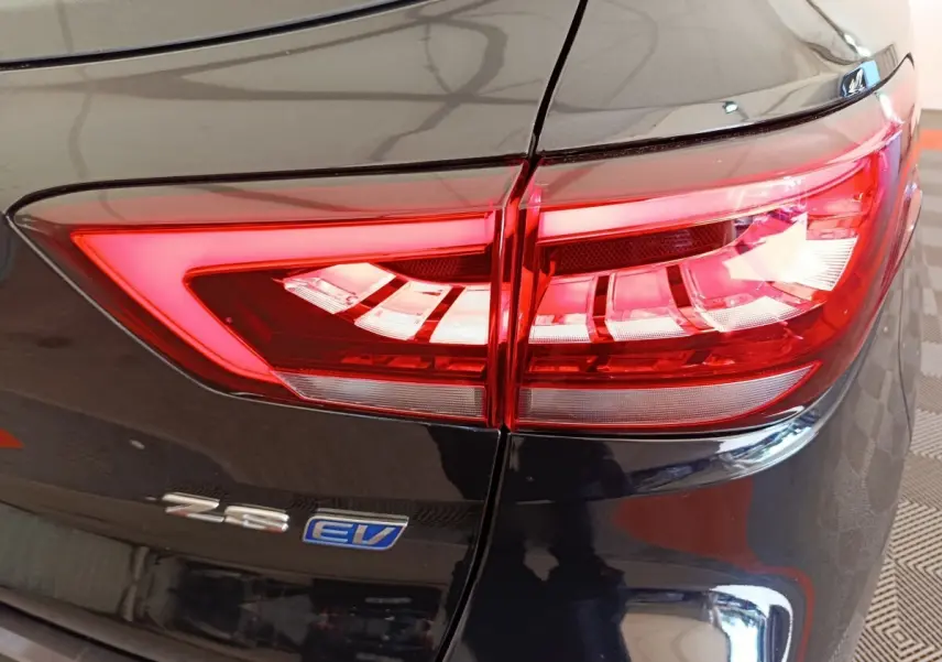 Gros plan sur le feu arrière droit rouge vif du MG ZS Luxury 70kWh noir électrique avec logo EV visible.