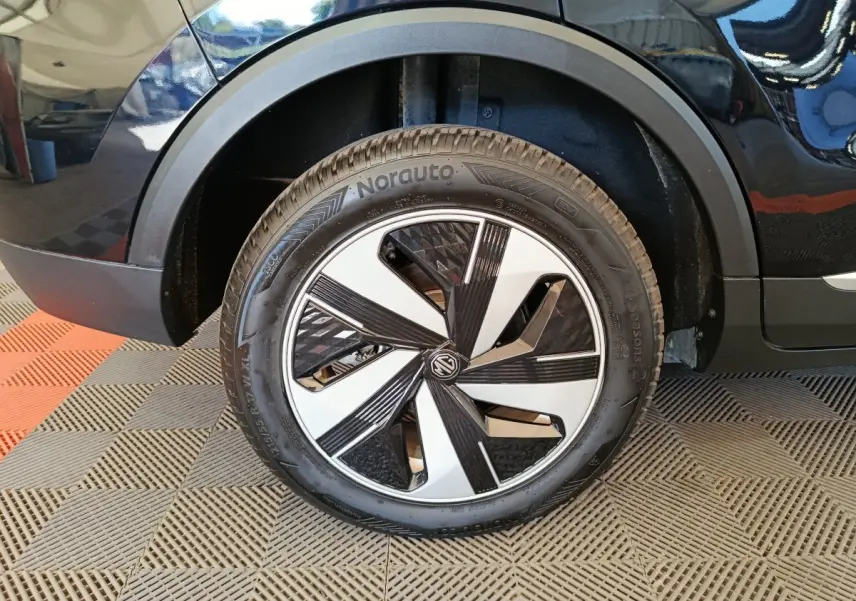 Gros plan sur la roue arrière droite du MG ZS Luxury 70kWh noir avec jante au design moderne bicolore.