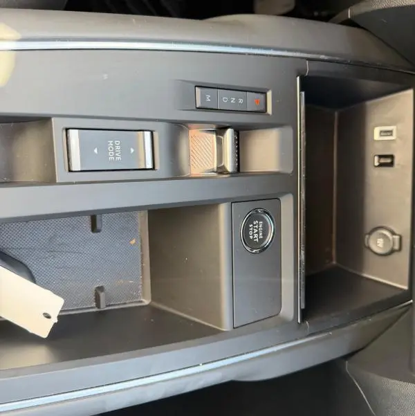 Vue rapprochée de la console centrale noire du Citroën C5 Aircross 2024 hybride, avec bouton start/stop et sélecteur de mode de conduite.