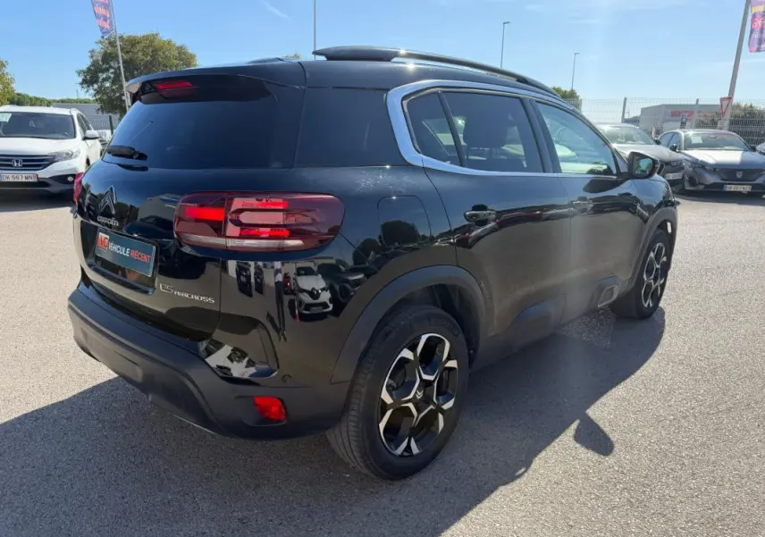 Vue 3/4 arrière droite d'un Citroën C5 Aircross hybride noir 2024 avec jantes distinctives et vitres teintées.