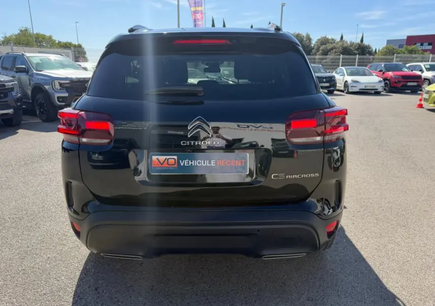 Vue arrière d’un Citroën C5 Aircross noir 2024 avec feux arrière allumés sur un parking extérieur.