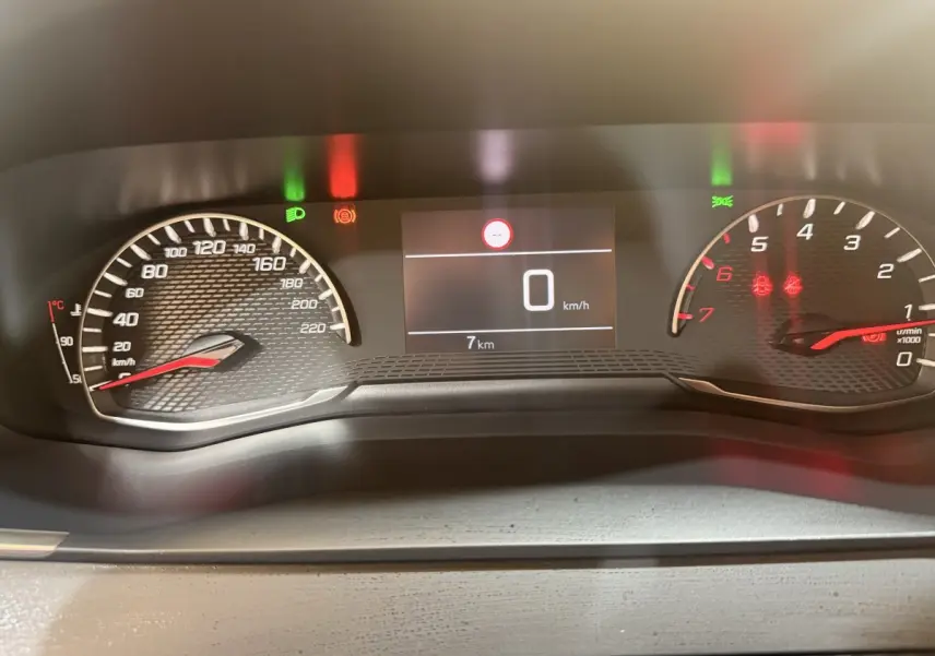 Tableau de bord numérique de Peugeot 208 blanc, affichage vitesse 0 km/h et compte-tours au ralenti.