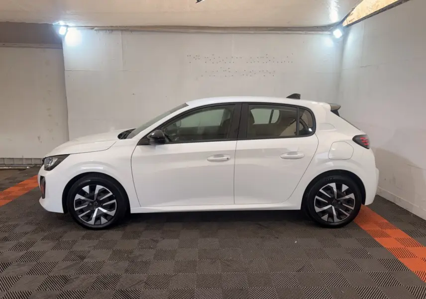 Peugeot 208 blanche vue de profil côté gauche dans un garage, avec jantes alliage et rétroviseurs noirs.
