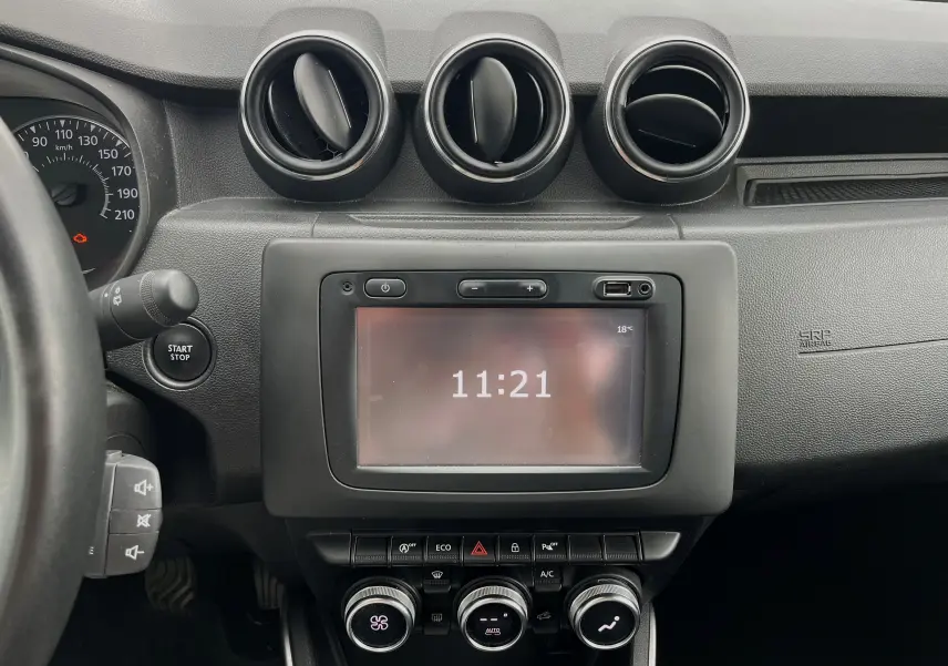 Tableau de bord du Dacia Duster 1.5 DCI 2018 en vue frontale, avec écran tactile et commandes de climatisation.