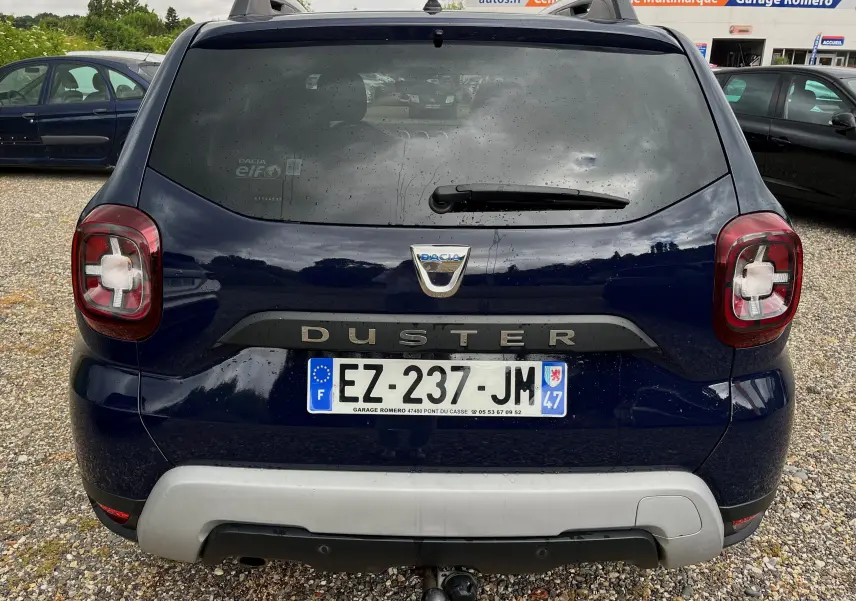 Vue arrière d'un Dacia Duster bleu marine 2018 avec logo et plaque d'immatriculation française visible.