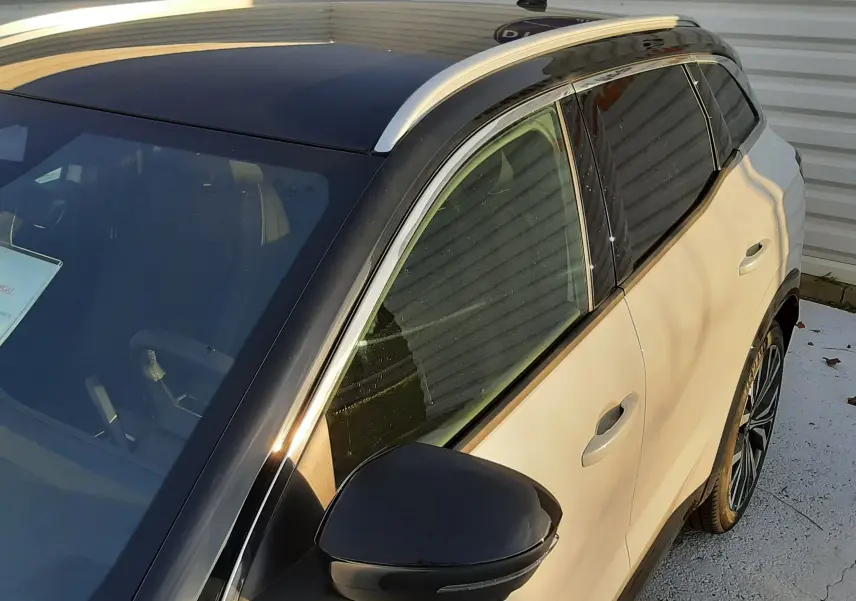 Vue 3/4 avant droit du Renault Austral 2025 blanc nacré avec toit noir et rétroviseur noir brillant.