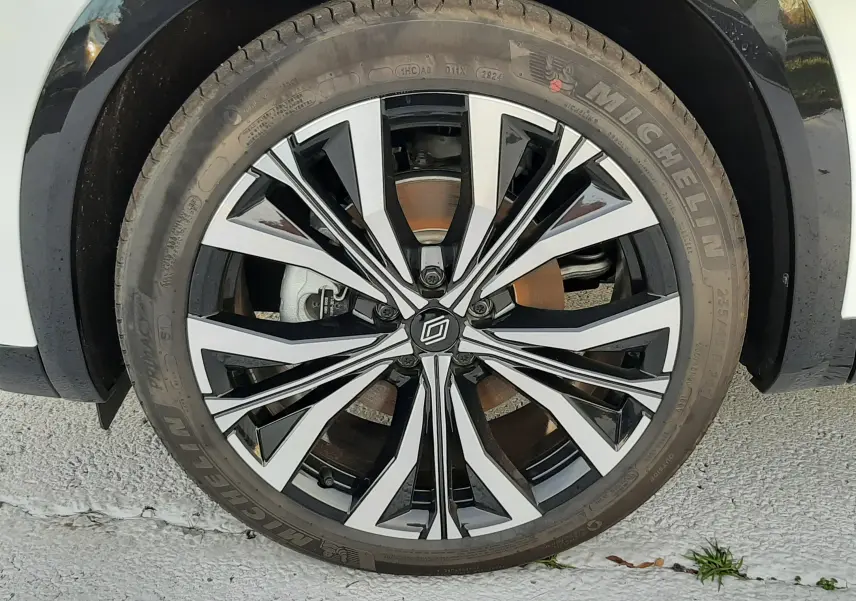 Gros plan sur la roue avant droite du Renault Austral blanc nacré avec jante alliage noire et argentée design moderne.