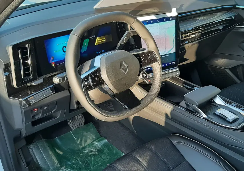Vue intérieure côté conducteur du Renault Austral 2025 hybride, tableau de bord numérique et écran tactile central lumineux.