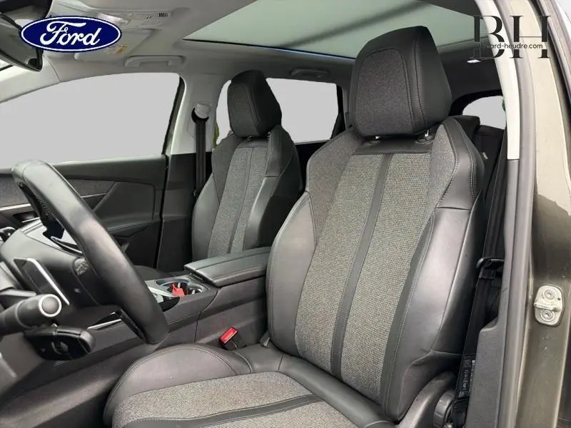 Vue intérieure avant du Peugeot 5008 gris Amazonite, sièges en tissu et cuir avec accoudoir central.