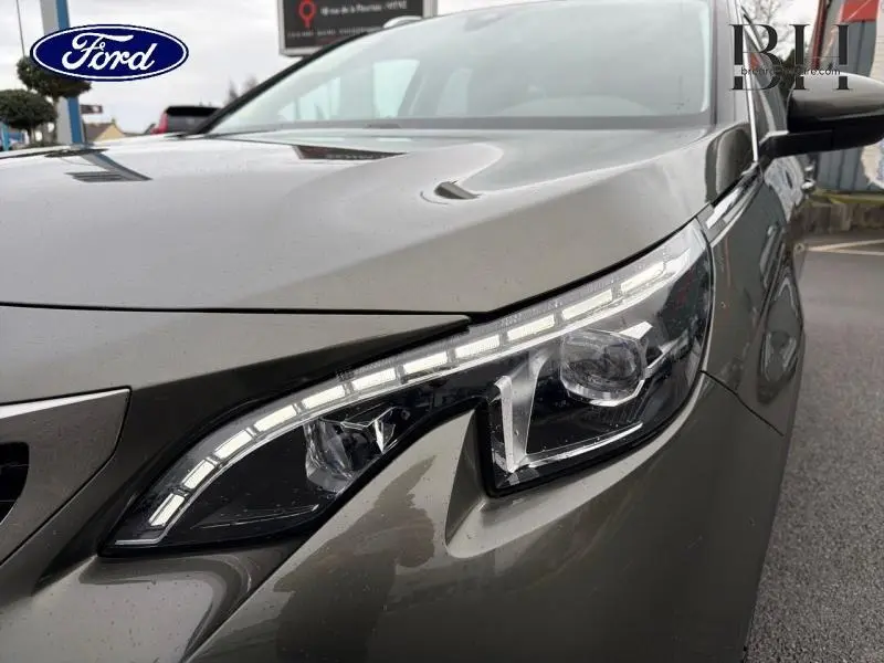 Gros plan sur le phare avant droit du Peugeot 5008 gris Amazonite avec LED distinctives et carrosserie lisse.