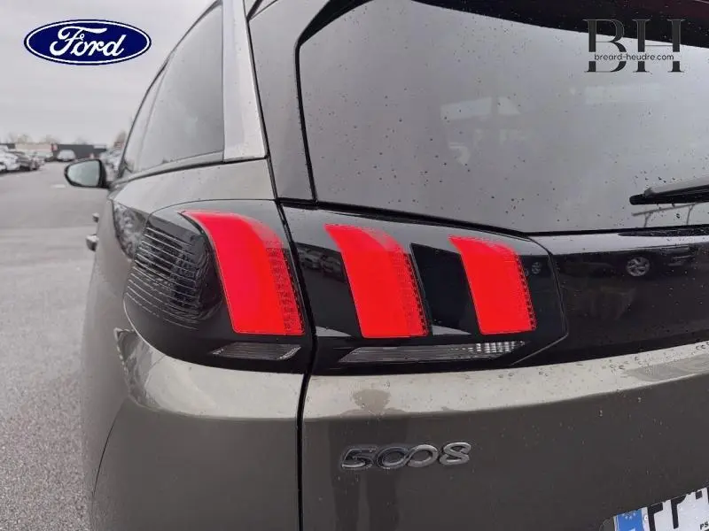 Gros plan sur le feu arrière droit rouge et noir du Peugeot 5008 gris Amazonite, avec logo 5008 visible sur le hayon.