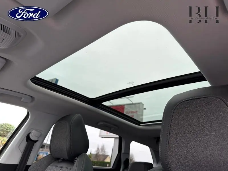 Vue intérieure du toit ouvrant panoramique et des sièges avant gris d'un Peugeot 5008 Gris Amazonite.