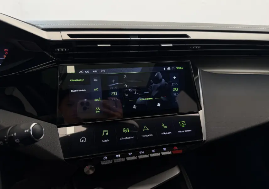 Vue rapprochée du tableau de bord noir de la Peugeot 308 Hybrid 136 e-DCS6 GT 2024 avec écran tactile central allumé.