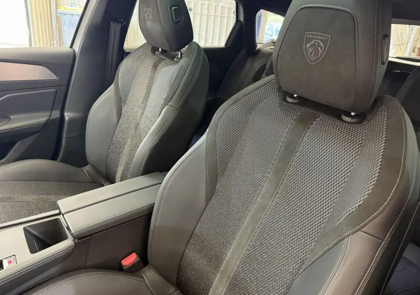 Vue rapprochée des sièges avant noirs en cuir et tissu avec logo Peugeot embossé sur les appuie-têtes.