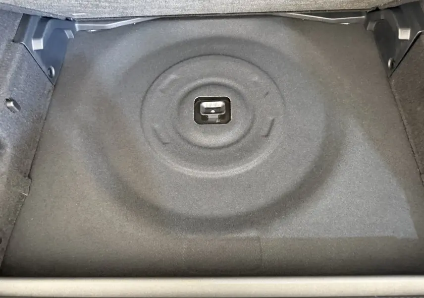 Vue plongeante sur le coffre vide de la Peugeot 308 Hybrid 136 e-DCS6 GT, revêtement gris foncé sans roue de secours visible.