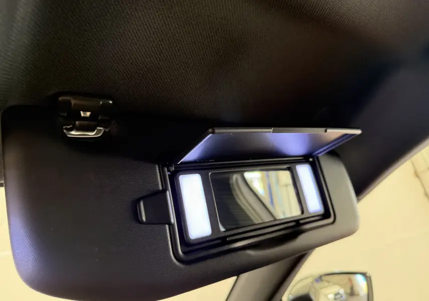 Miroir de courtoisie éclairé sur pare-soleil côté conducteur dans l’habitacle d’une Peugeot 308 Hybrid blanc 2024.