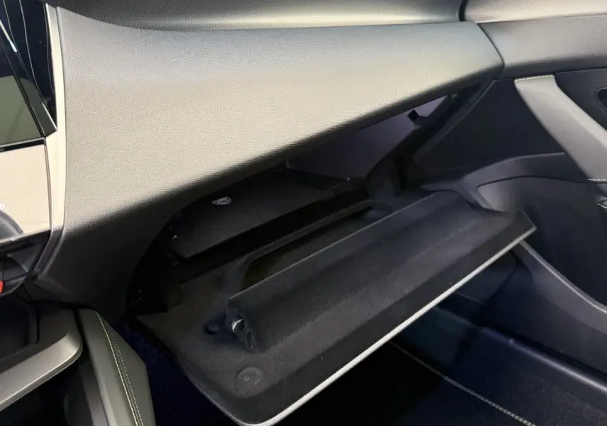 Intérieur de la Peugeot 308 Hybrid 136 e-DCS6 GT 2024, vue du vide-poche passager ouvert avec finition noire.