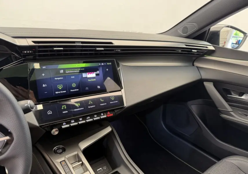Intérieur Peugeot 308 Hybrid 136 e-DCS6 GT 2024, vue côté passager, tableau de bord noir avec écran tactile central.