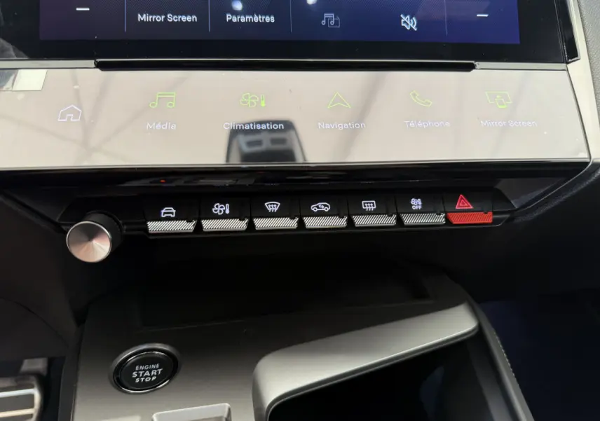 Vue rapprochée du tableau de bord noir du Peugeot 308 Hybrid 2024, avec écran tactile et boutons de commande éclairés.