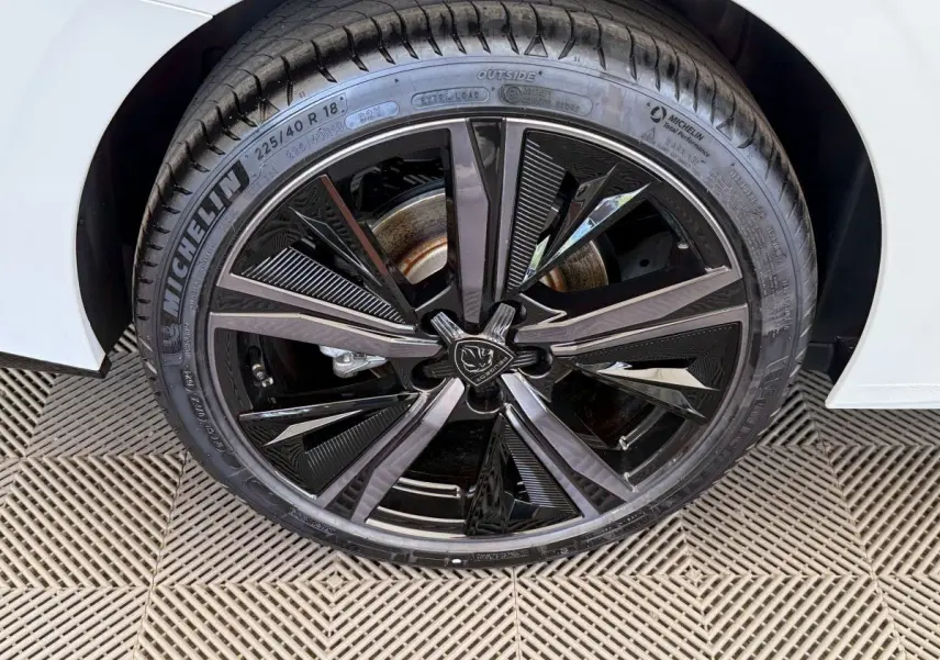 Gros plan sur la roue avant droite noire brillante d'une Peugeot 308 Hybrid blanche, avec pneu Michelin visible.