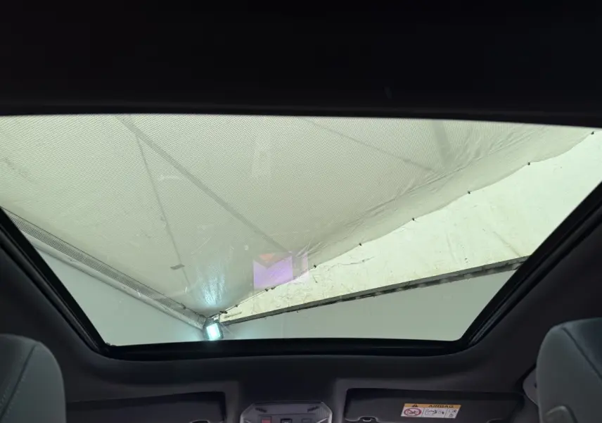 Toit panoramique ouvert vu de l'intérieur arrière d'une Peugeot 308 Hybrid 136 e-DCS6 GT blanche.