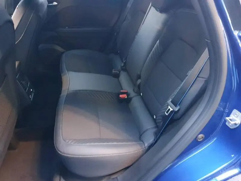 Vue côté droit sur la banquette arrière en cuir noir du Renault Captur Bleu Iron avec ceinture de sécurité bleue visible.