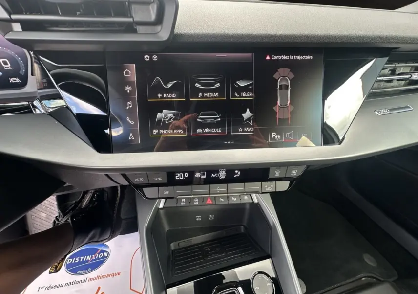 Vue intérieure centrée sur la console centrale et l’écran tactile de l’Audi A3 30 TFSI blanc, affichant les commandes multimédia.