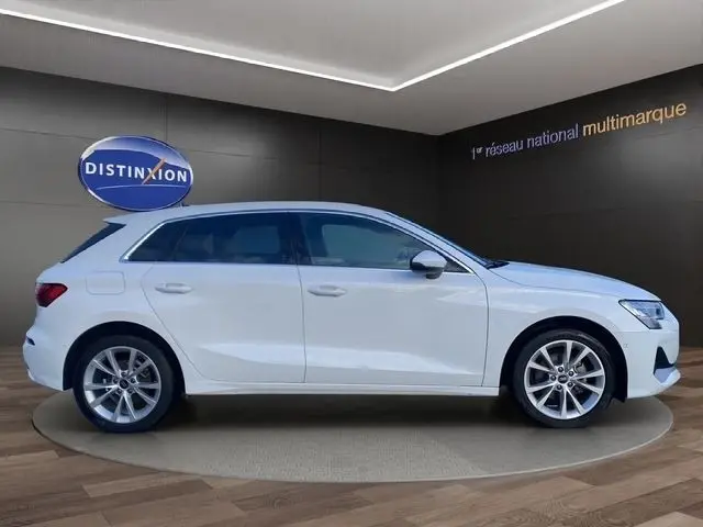 Vue de profil côté gauche de l'Audi A3 30 TFSI blanc 2024 sur plateau en showroom avec jantes alliage argentées.