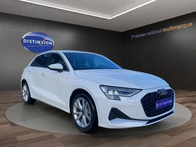 Audi A3 30 TFSI blanche vue 3/4 avant droit, avec calandre noire distinctive et jantes argentées en showroom