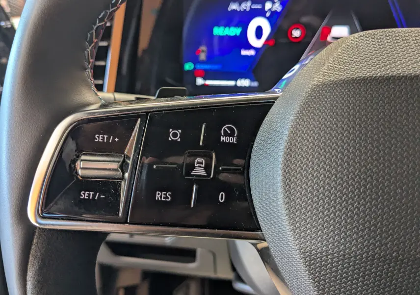Gros plan sur les commandes au volant du Renault Espace VI E-Tech, avec affichage digital bleu en arrière-plan.