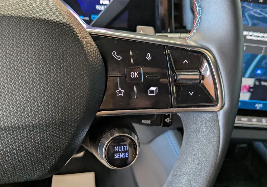Gros plan sur les commandes gauche du volant noir avec surpiqûres bleues du Renault Espace VI E-Tech Full Hybrid 2025.