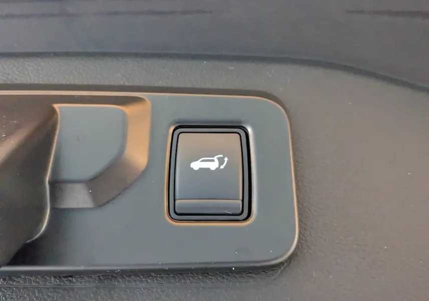 Gros plan sur le bouton intérieur noir d'ouverture électrique du hayon du Renault Espace VI E-Tech Full Hybrid 2025.