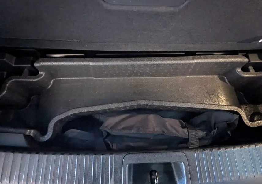 Vue rapprochée du rangement sous le plancher du coffre du Renault Espace VI noir Étoile, avec une housse noire visible.