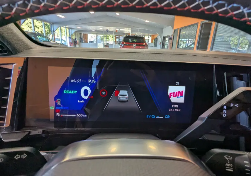 Vue intérieure du tableau de bord numérique du Renault Espace VI hybride, affichant la vitesse à 0 km/h et la radio FUN.