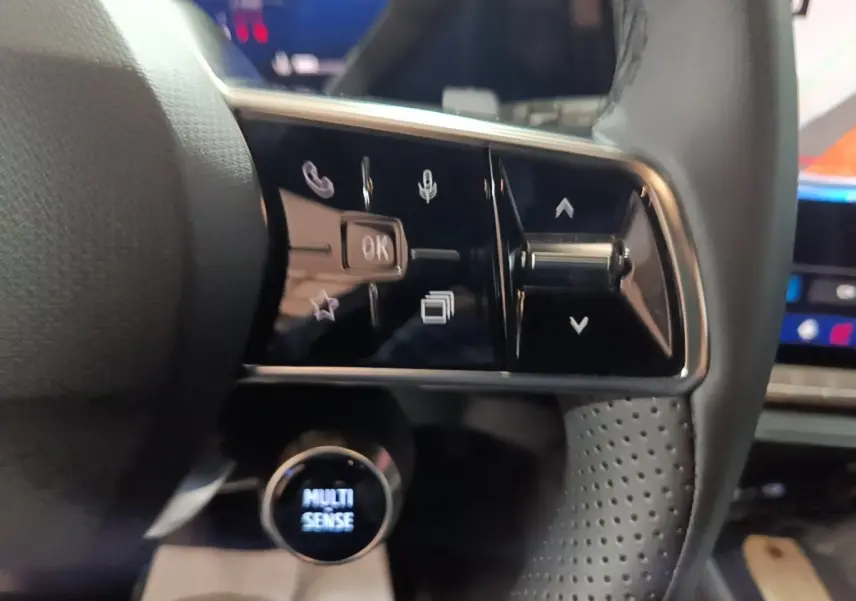 Gros plan sur les commandes multifonctions en cuir du volant du Renault Austral 2024, avec bouton rotatif Multi Sense.